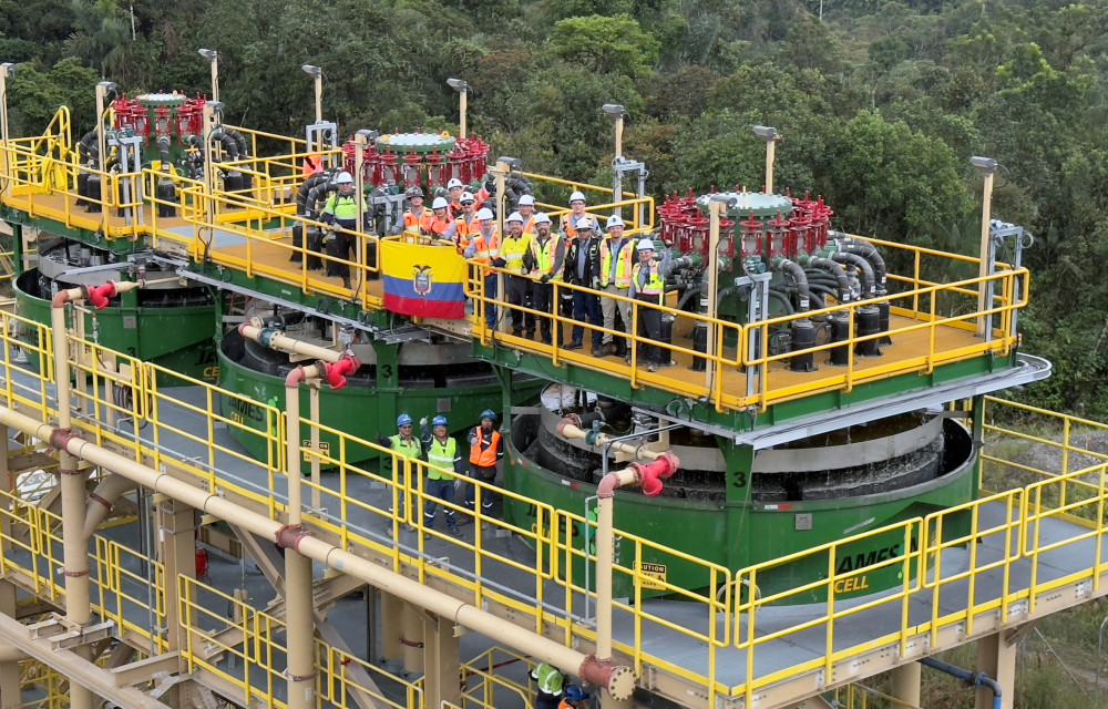 Group of workers in safety gear standing on top of three newly commissioned Jameson Cells at Lundin Gold’s Fruta del Norte mine in Ecuador, with forest backdrop.